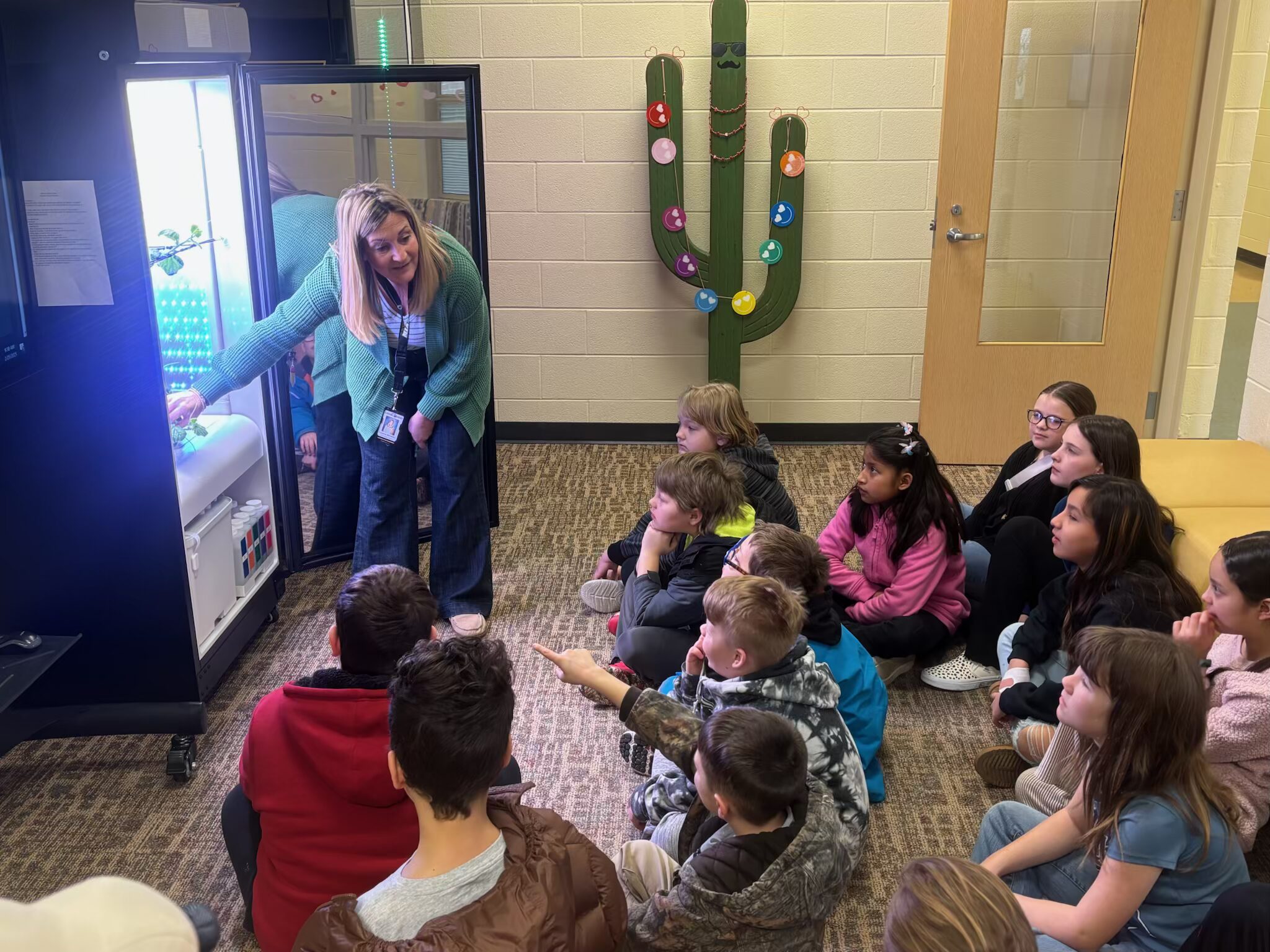 "A teacher showing hydroponic systems to elementary school students in a classroom."